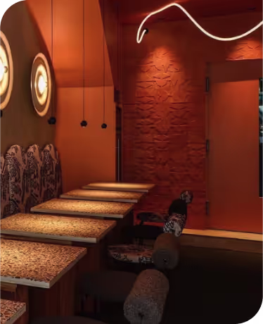 Un coin cosy d’un restaurant avec une ambiance chaleureuse, des tables en bois, des banquettes avec un motif noir et blanc et un éclairage suspendu tamisé.